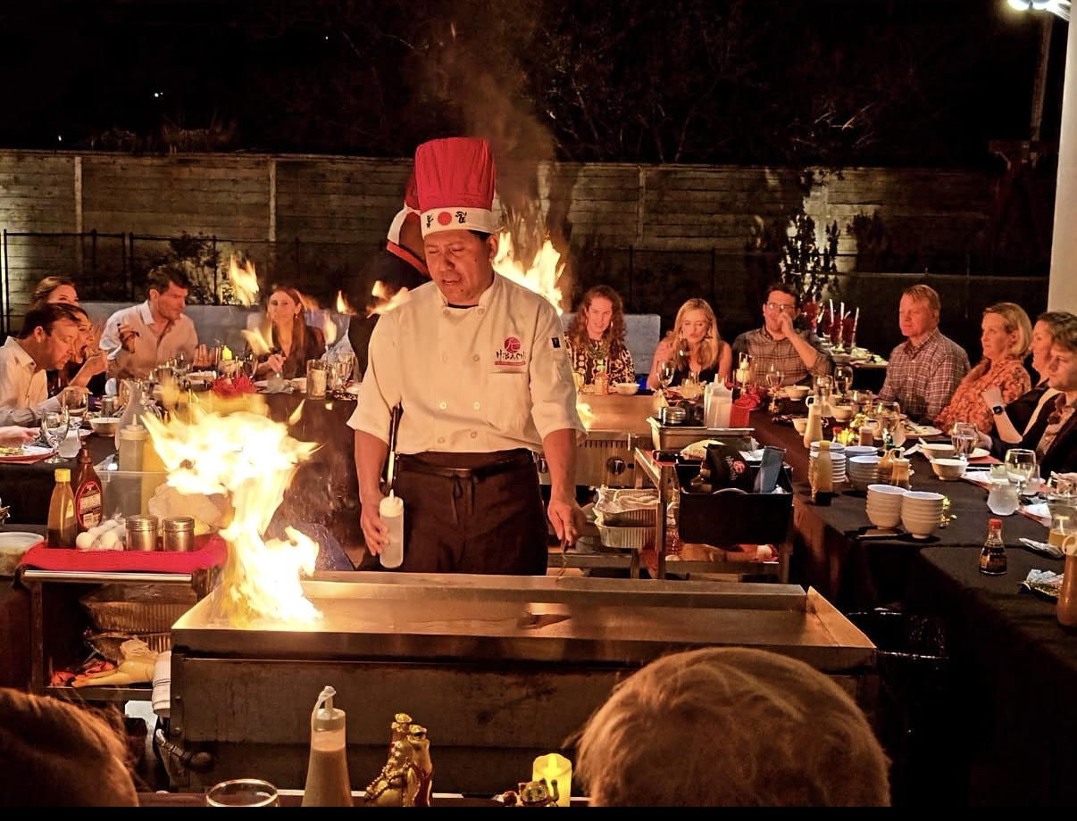 Hibachi chef cooking with flames at an evening party